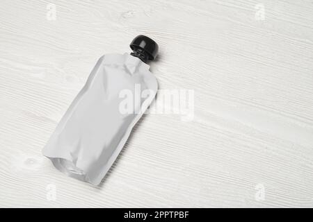 White empty plastic pouch for baby food, fruit puree on wood table. Mock-up template for design. Stock Photo