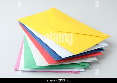 Stack of colorful paper envelopes on light background Stock Photo