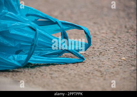 Handles of a blue plastic bag lying on the ground. Stock Photo