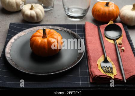 Seasonal table setting with pumpkins and autumn leaves on grey background Stock Photo