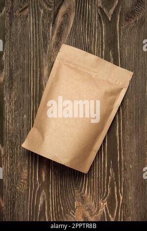 Brown kraft paper pouch bag on wood table. Mock-up template for design. Stock Photo