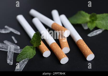 Cigarettes, menthol crystals and mint on black background, closeup Stock Photo