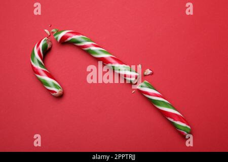 Broken sweet Christmas candy cane on red background, top view Stock Photo