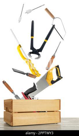 Different carpenter's tools falling into wooden box on white background Stock Photo