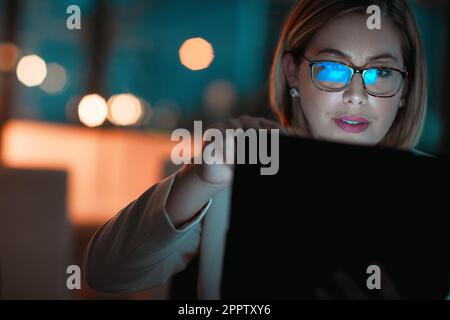 Connected through the night. a businesswoman using a digital tablet during a late night at work. Stock Photo