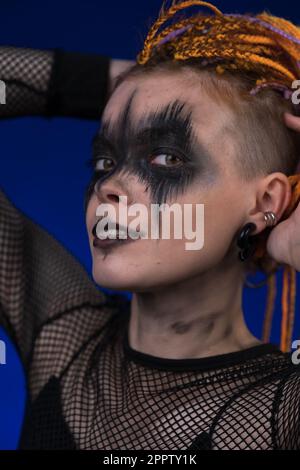 Headshot of young woman with horror black stage make up painted on face and colored without dangerous dreadlocks hairstyle. Studio shot portrait Stock Photo