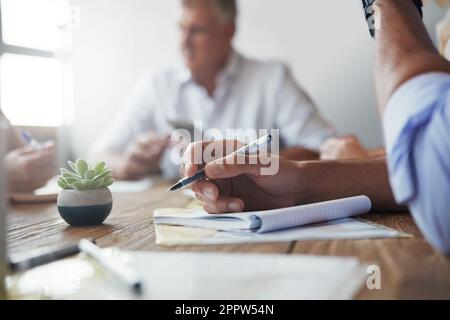 Paying close attention. an unidentifiable businessman making notes during a meeting in the office. Stock Photo