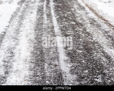 icy surface of asphalt road covered with fine freshly fallen snow on overcast winter day Stock Photo