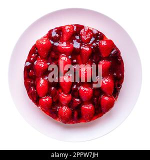 top view of sweet cake with strawberries and cherries on pink plate cutout on white background Stock Photo