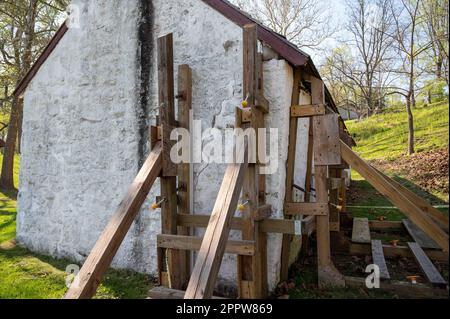 Wooden support scaffolding braces cracked wall of colonial cottage Stock Photo