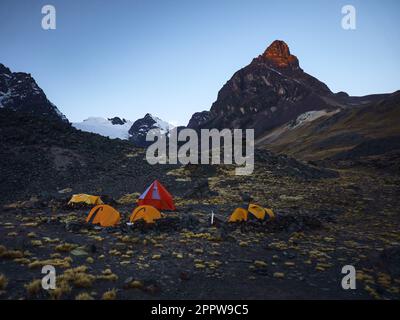 A nighttime scene featuring several camping tents in front of mountain landscape in Condoriri Bolivia Stock Photo