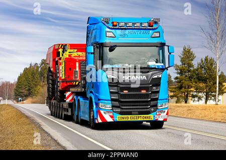 Blue Scania R650 truck semi low-loader trailer Montrans transports Sandvik mining equipment as exceptional load on road. Salo, Finland. April 6, 2023. Stock Photo
