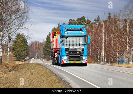 Blue Scania R650 truck semi low-loader trailer Montrans transports Sandvik mining equipment as exceptional load on road. Salo, Finland. April 6, 2023. Stock Photo
