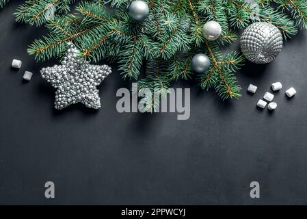 Christmas composition. Christmas decor, pine cones, fir branches, silver star and ornaments on black background, top view, copy space. Stock Photo