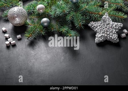 Christmas composition. Christmas decor, pine cones, fir branches, silver star and ornaments on black background, top view, copy space. Stock Photo