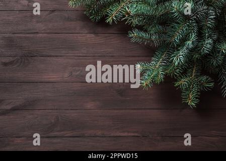 Christmas background with pine branches on dark wooden table, top view, copy space. Merry Christmas and happy New Year celebration concept. Stock Photo