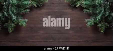 Christmas background with pine branches on dark wooden table, top view, copy space. Merry Christmas celebration concept, winter holidays banner. Stock Photo