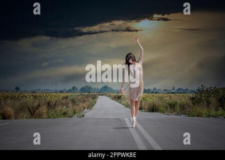Female ballet dancer dancing in the middle of the road at sunset, Bulgaria Stock Photo