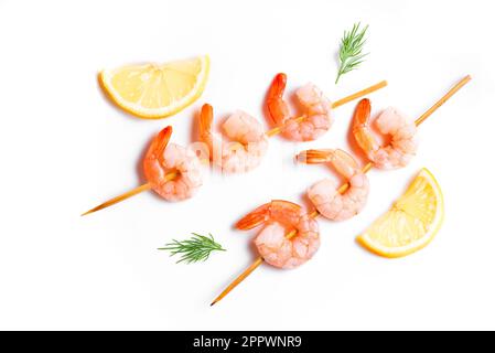 Shrimp skewers isolated on white background. Fresh prawn seafood skewer kebab close up with dill and lemon, design element. Stock Photo