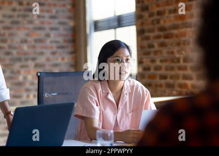 Asian female creative discussing project with colleagues at design meeting Stock Photo