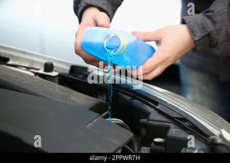 Pouring blue antifreeze liquid for washing car glass closeup Stock Photo