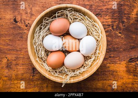 Whole chicken eggs in bowl on the wooden table. Top view. Stock Photo