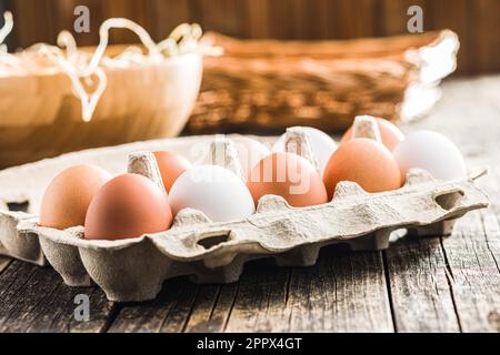 Whole chicken eggs in eggbox on the wooden table. Stock Photo