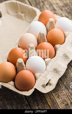 Whole chicken eggs in eggbox on the wooden table. Stock Photo