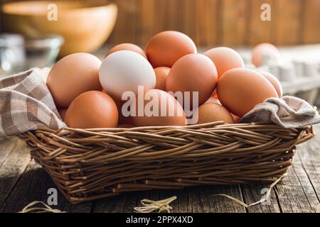 Whole chicken eggs in basket on the wooden table. Stock Photo