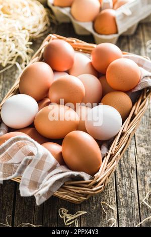Whole chicken eggs in basket on the wooden table. Stock Photo