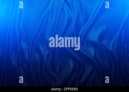 Silk fabric, abstract wavy background of black satin fabric in blue light Stock Photo