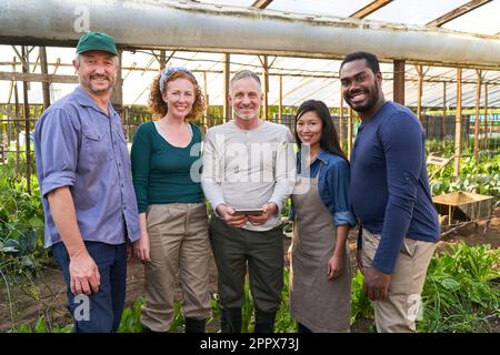 Portrait of farmer's team in greenhouse working with tablet computer for organization Stock Photo