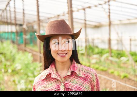 Smiling female farmer wearing checked shirt while looking away at farm Stock Photo
