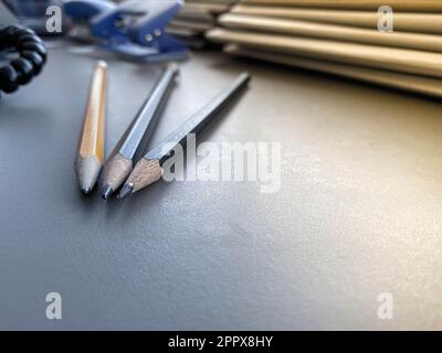 Three pencils lie sharply sharpened next to folders with sheets of paper and documents on the working business desk in the office. Stationery. Stock Photo
