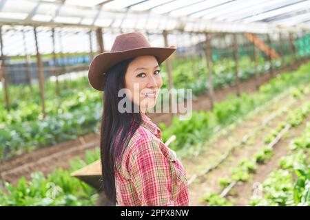 Side view of female farmer wearing hat while standing in greenhouse Stock Photo
