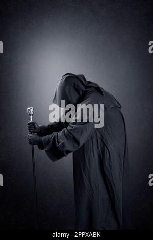 Wizard with hooded cape and magic staff over dark misty background Stock Photo