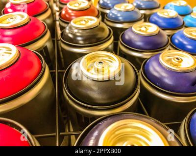 spray cans of paint are on display behind a metal mesh. paint sprayers of various colors. graffiti art, car painting. balloons are filled with multi-c Stock Photo