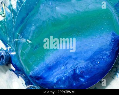The process of creating a home-made trendy abstract modern pattern painted with a brush of acrylic blue multi-colored resin on a round wooden board Stock Photo