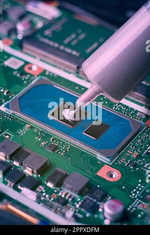 squeezing fresh thermal paste compound on laptop processor, close-up view of gray thermal grease for better cpu cooling, computer hardware, repair Stock Photo