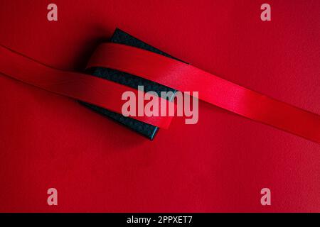 Black gift box with red ribbon on bright red background Stock Photo