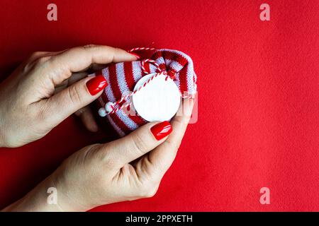 Anonymous woman holds the knitted gift bag on red background Stock Photo