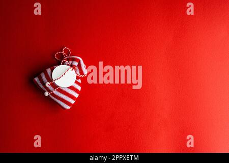 Knitted stripped red and white gift bag on bright red background Stock Photo