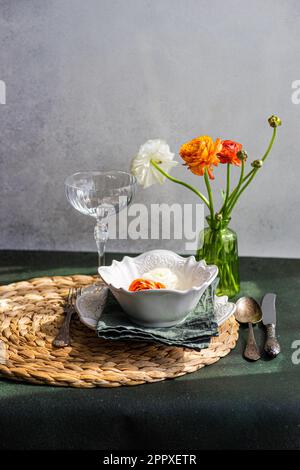 Table setting with Ranunculus flowers on concrete background Stock Photo