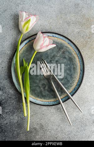 Top view of table setting with fresh tulip flowers on concrete background Stock Photo