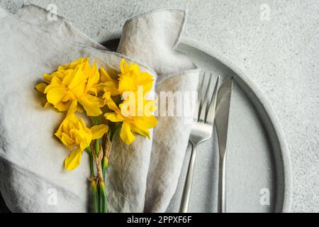 Top view of monochrome concrete table setting with daffodil flowers on the grey cement background Stock Photo