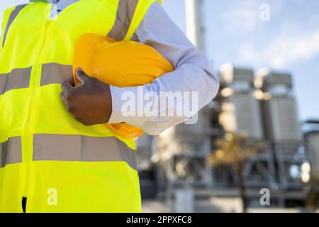 crop anonymous African American female engineer in uniform and helmet standing on construction site during work Stock Photo