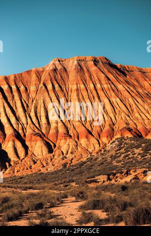 Picturesque view of rough rocky mountains with uneven peaks and dry brown surface located under blue sky in Bardenas Reales desert Stock Photo