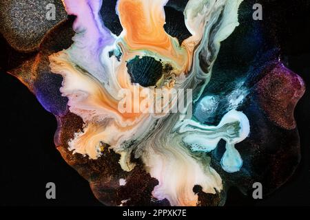 Spills of multicolored metallic dye mixing and spreading on black background Stock Photo
