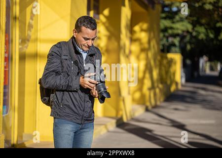 Latino photographer checking a photograph on his camera with copy space. Stock Photo