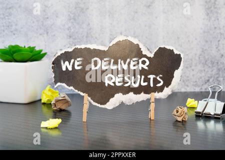 We deliver Results text on a black folder near a cup of coffee. light wooden background. Stock Photo